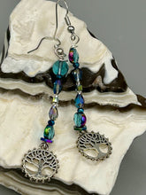 Load image into Gallery viewer, This captivating set of earrings boasts an exquisite range of intense blues and purples, accented with a warm touch of gold and green. The dangling silver plated tree of life charm adds a beautiful finishing touch.  Measurements: 2 1/2” in length