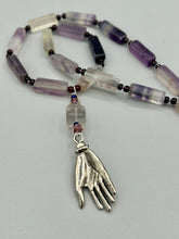 Load image into Gallery viewer, This nature-inspired accessory features an array of unique hues, including rectangular-shaped rainbow fluorite stone beads, round amethyst beads and dark purple glass beads. The secure hook-eye clasp makes it perfect for day to night wear, allowing you to add a touch of summer to your wardrobe. The necklace is further complemented by a large square-shaped rainbow fluorite bead and a lucky hand charm. Measurements: Necklace: 18", Lucky hand pendant 3"
