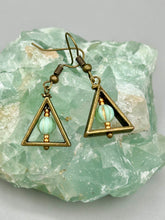 Load image into Gallery viewer, Antique antique brass plated steel ear-wire French Hook Earrings. Antique brass triangle dangle earrings feature a light mint green melon Czech faceted round glass beads with a tint of light gold shimmer. Unique style earrings display a beautiful complimentary tones between the light mint green beads and the warm brass tone. Antique antique brass plated steel ear-wire French Hook Earrings. Measurements: 1" length