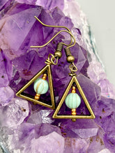 Load image into Gallery viewer, Antique antique brass plated steel ear-wire French Hook Earrings. Antique brass triangle dangle earrings feature a light mint green melon Czech faceted round glass beads with a tint of light gold shimmer. Unique style earrings display a beautiful complimentary tones between the light mint green beads and the warm brass tone. Antique antique brass plated steel ear-wire French Hook Earrings. Measurements: 1" length