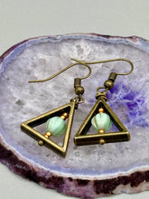 Load image into Gallery viewer, Antique antique brass plated steel ear-wire French Hook Earrings. Antique brass triangle dangle earrings feature a light mint green melon Czech faceted round glass beads with a tint of light gold shimmer. Unique style earrings display a beautiful complimentary tones between the light mint green beads and the warm brass tone. Antique antique brass plated steel ear-wire French Hook Earrings. Measurements: 1" length