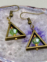 Load image into Gallery viewer, Antique antique brass plated steel ear-wire French Hook Earrings. Antique brass triangle dangle earrings feature a light green round glass beads with tiny small gold tone beads. Unique style earrings display a beautiful complimentary tones between the light green beads and the warm brass tone. Antique antique brass plated steel ear-wire French Hook Earrings. Measurements: 1" length
