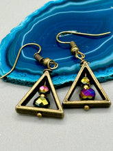 Load image into Gallery viewer, Antique brass triangle dangle earrings feature a purple tone glass bead with an iridescent shimmer finish showcasing hues of gold, purple, blue and pink. Unique style earrings display a beautiful contras between the dark and cool tone glass beads and the warm brass tone. Antique brass plated steel ear-wire French Hook Earrings. Measurements: 1" length
