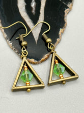 Load image into Gallery viewer, Antique antique brass plated steel ear-wire French Hook Earrings. Antique brass triangle dangle earrings feature a light green round glass beads with tiny small gold tone beads. Unique style earrings display a beautiful complimentary tones between the light green beads and the warm brass tone. Antique antique brass plated steel ear-wire French Hook Earrings. Measurements: 1" length