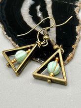 Load image into Gallery viewer, Antique antique brass plated steel ear-wire French Hook Earrings. Antique brass triangle dangle earrings feature a light mint green melon Czech faceted round glass beads with a tint of light gold shimmer. Unique style earrings display a beautiful complimentary tones between the light mint green beads and the warm brass tone. Antique antique brass plated steel ear-wire French Hook Earrings. Measurements: 1" length