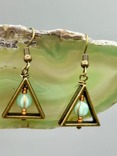 Load image into Gallery viewer, Antique antique brass plated steel ear-wire French Hook Earrings. Antique brass triangle dangle earrings feature a light mint green melon Czech faceted round glass beads with a tint of light gold shimmer. Unique style earrings display a beautiful complimentary tones between the light mint green beads and the warm brass tone. Antique antique brass plated steel ear-wire French Hook Earrings. Measurements: 1" length