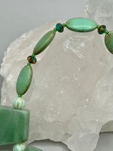 Load image into Gallery viewer, This expertly crafted necklace features a large trapezoid-shaped green aventurine stone, mint green melon beads with gold shimmer, and teal glass beads with an amber tone. Intricately arranged together, this piece offers genuine stones and an elegant bohemian style. Measurements: Necklace is 19"