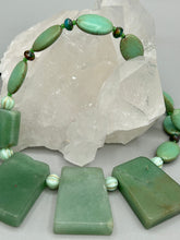 Load image into Gallery viewer, This expertly crafted necklace features a large trapezoid-shaped green aventurine stone, mint green melon beads with gold shimmer, and teal glass beads with an amber tone. Intricately arranged together, this piece offers genuine stones and an elegant bohemian style. Measurements: Necklace is 19"