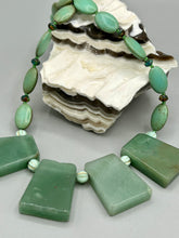 Load image into Gallery viewer, This expertly crafted necklace features a large trapezoid-shaped green aventurine stone, mint green melon beads with gold shimmer, and teal glass beads with an amber tone. Intricately arranged together, this piece offers genuine stones and an elegant bohemian style. Measurements: Necklace is 19"