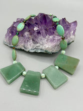 Load image into Gallery viewer, This expertly crafted necklace features a large trapezoid-shaped green aventurine stone, mint green melon beads with gold shimmer, and teal glass beads with an amber tone. Intricately arranged together, this piece offers genuine stones and an elegant bohemian style. Measurements: Necklace is 19"