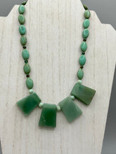 Load image into Gallery viewer, This expertly crafted necklace features a large trapezoid-shaped green aventurine stone, mint green melon beads with gold shimmer, and teal glass beads with an amber tone. Intricately arranged together, this piece offers genuine stones and an elegant bohemian style. Measurements: Necklace is 19"