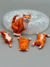 Load image into Gallery viewer, Cat lovers dream, this hand-crafted orange tabby cat magnet art is the purrfect decoration on refrigerators, lockers, cubicles or toolboxes. The set includes three mini cat figurines, featuring emerald green eyes. Measurements: H 2” x W 1/2” x D 3/8” - Cat Magnet H 2” x W 3/8” x D 3/8” - Cat Figurines