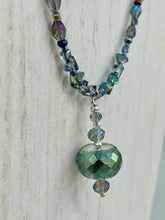 Load image into Gallery viewer, Make a bold statement with this shimmery aqua blue and blue tones glass beaded necklace. The round faceted shaped pendant compliments the cool tones of the necklace, perfect for adding a rich pop of color to any Spring outfit. The draped design gives this piece an elegant, bohemian look. Measurements: Necklace is 18” in length, pendant is 1 1/2”