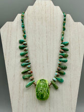 Load image into Gallery viewer, This powerful statement piece necklace features an eye-catching hand sculpted dark blue clay scarab beetle pendant. Adorned with green magnesite and serpentine teintee stone beaded necklace, this dramatic necklace artfully wraps around the neck, conveying an elegant and bold style. Necklace is 20 1/4" in length