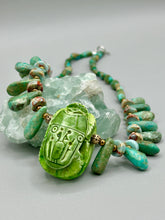 Load image into Gallery viewer, This powerful statement piece necklace features an eye-catching hand sculpted dark blue clay scarab beetle pendant. Adorned with green magnesite and serpentine teintee stone beaded necklace, this dramatic necklace artfully wraps around the neck, conveying an elegant and bold style. Necklace is 20 1/4" in length