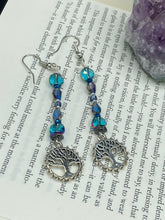 Load image into Gallery viewer, This captivating set of earrings boasts an exquisite range of intense blues and purples, accented with a warm touch of gold and green. The dangling silver plated tree of life charm adds a beautiful finishing touch.  Measurements: 2 1/2” in length