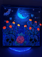 Load image into Gallery viewer, This carefully crafted polymer clay wall art showcases a wood frame adorned with a crescent moon and stars motifs. A striking dark palette of deep sky tones, including royal blue to black, further enhances the piece. Delicate cacti plants bloom with light pink/purple flowers, with spooky skulls are incorporated among the cacti plant and a finishing touch of a tiny flying bat motif. Measurements: H 6 3/4" x W 6 3/4” x D 1 1/4"