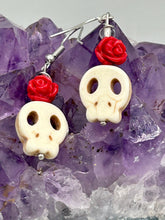 Load image into Gallery viewer, These stylish skull earrings are perfect for adding a unique flair to any outfit. Whether you're looking for a Dia De Los Muertos accessory or simply looking to draw inspiration, these goth pieces perfectly capture the vampire goth, witchy, dark, Chingona Cabrona, Latina Chicana styles. Howlite stone skull bead with red quartzize floral beads.  Measurements: 1 1/4 ” in length