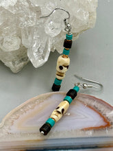 Load image into Gallery viewer, These stylish skull earrings are perfect for adding a unique flair to any outfit. Whether you're looking for a Dia De Los Muertos accessory or simply looking to draw inspiration, these goth pieces perfectly capture the vampire goth, witchy, dark, Chingona Cabrona, Latina Chicana styles. Skull-shaped bone beads adorned with dark brown, turquoise, and gold beaded earrings make up this unique set of earrings. Measurements: 1 1/2 ” in length