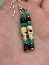Load image into Gallery viewer, These stylish skull earrings are perfect for adding a unique flair to any outfit. Whether you're looking for a Dia De Los Muertos accessory or simply looking to draw inspiration, these goth pieces perfectly capture the vampire goth, witchy, dark, Chingona Cabrona, Latina Chicana styles. Skull-shaped bone beads adorned with dark brown, turquoise, and gold beaded earrings make up this unique set of earrings. Measurements: 1 1/2 ” in length