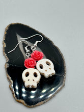 Load image into Gallery viewer, These stylish skull earrings are perfect for adding a unique flair to any outfit. Whether you're looking for a Dia De Los Muertos accessory or simply looking to draw inspiration, these goth pieces perfectly capture the vampire goth, witchy, dark, Chingona Cabrona, Latina Chicana styles. Crafted with Howlite stone skull beads and pink coral quartzize floral beaded earrings, this jewelry set is a unique stunning statement piece.  Measurements: 1 1/4 ” in length