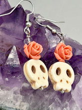 Load image into Gallery viewer, These stylish skull earrings are perfect for adding a unique flair to any outfit. Whether you're looking for a Dia De Los Muertos accessory or simply looking to draw inspiration, these goth pieces perfectly capture the vampire goth, witchy, dark, Chingona Cabrona, Latina Chicana styles. Crafted with Howlite stone skull beads and peachy coral quartzize floral beaded earrings, this jewelry set is a unique stunning statement piece.  Measurements: 1 1/4 ” in length