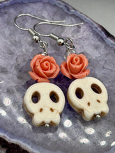 Load image into Gallery viewer, These stylish skull earrings are perfect for adding a unique flair to any outfit. Whether you're looking for a Dia De Los Muertos accessory or simply looking to draw inspiration, these goth pieces perfectly capture the vampire goth, witchy, dark, Chingona Cabrona, Latina Chicana styles. Crafted with Howlite stone skull beads and peachy coral quartzize floral beaded earrings, this jewelry set is a unique stunning statement piece.  Measurements: 1 1/4 ” in length