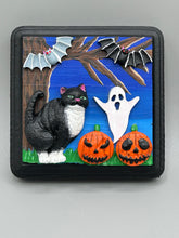 Load image into Gallery viewer, This handcrafted Halloween theme polymer clay wall art boasts a square-shaped wood frame with hand sculpted tuxedo cat, gray and black bats, jack-o-lantern and ghost motifs. Its cool sky hues, including light to dark blues are further complemented by the black frame adding an extra layer of sophistication to the spooky cool-toned artwork.  Measurements: H 4" x W 4” x D 1 1/2"