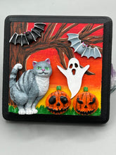 Load image into Gallery viewer, This handcrafted Halloween theme polymer clay wall art boasts a square-shaped wood frame with hand sculpted gray tabby cat, gray and black bats, jack-o-lantern and ghost motifs. Its warm sky hues, including yellow, to orange to dark red are further complemented by the black frame adding an extra layer of sophistication to the spooky warm-toned artwork.  Measurements: H 4" x W 4” x D 1 1/2"