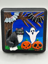 Load image into Gallery viewer, This handcrafted Halloween theme polymer clay wall art boasts a square-shaped wood frame with hand sculpted tuxedo cat, gray and black bats, jack-o-lantern and ghost motifs. Its cool sky hues, including light to dark blues are further complemented by the black frame adding an extra layer of sophistication to the spooky cool-toned artwork.  Measurements: H 4" x W 4” x D 1 1/2"