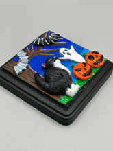 Load image into Gallery viewer, This handcrafted Halloween theme polymer clay wall art boasts a square-shaped wood frame with hand sculpted tuxedo cat, gray and black bats, jack-o-lantern and ghost motifs. Its cool sky hues, including light to dark blues are further complemented by the black frame adding an extra layer of sophistication to the spooky cool-toned artwork.  Measurements: H 4" x W 4” x D 1 1/2"