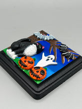 Load image into Gallery viewer, This handcrafted Halloween theme polymer clay wall art boasts a square-shaped wood frame with hand sculpted tuxedo cat, gray and black bats, jack-o-lantern and ghost motifs. Its cool sky hues, including light to dark blues are further complemented by the black frame adding an extra layer of sophistication to the spooky cool-toned artwork.  Measurements: H 4" x W 4” x D 1 1/2"