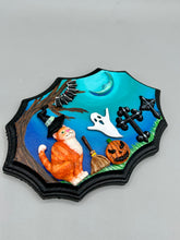 Load image into Gallery viewer, This captivating starry night orange tabby kitty paying a visit to the cemetery is artfully crafted with a black wood frame and a dark blue hues for an eye-catching captivating nocturnal effect art piece. The orange tabby, dressed in a witch's hat, pays a visit to the cemetery accompanied by a broom and a jack-o-lantern. This bewitching and whimsical Halloween-themed art piece adds a one-of-a-kind Halloween touch to any home or office. Measurements: H 5" x W 7” x D 1 1/2"