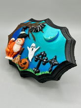 Load image into Gallery viewer, This captivating starry night orange tabby kitty paying a visit to the cemetery is artfully crafted with a black wood frame and a dark blue hues for an eye-catching captivating nocturnal effect art piece. The orange tabby, dressed in a witch's hat, pays a visit to the cemetery accompanied by a broom and a jack-o-lantern. This bewitching and whimsical Halloween-themed art piece adds a one-of-a-kind Halloween touch to any home or office. Measurements: H 5" x W 7” x D 1 1/2"