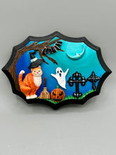 Load image into Gallery viewer, This captivating starry night orange tabby kitty paying a visit to the cemetery is artfully crafted with a black wood frame and a dark blue hues for an eye-catching captivating nocturnal effect art piece. The orange tabby, dressed in a witch's hat, pays a visit to the cemetery accompanied by a broom and a jack-o-lantern. This bewitching and whimsical Halloween-themed art piece adds a one-of-a-kind Halloween touch to any home or office. Measurements: H 5" x W 7” x D 1 1/2"