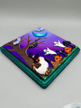 Load image into Gallery viewer, This captivating starry night calico kitty in the cemetery is artfully crafted with a black wood frame with a green iridescent finish and a dark purple hue background for an eye-catching and captivating nocturnal effect art piece. This kitty cat is dressed in a witch's hat while paying a visit to the cemetery accompanied by a broom and a jack-o-lantern and bat friends. This bewitching and whimsical Halloween-themed art piece adds a one-of-a-kind Halloween touch to any home or office.