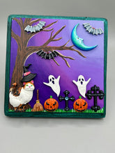 Load image into Gallery viewer, This captivating starry night calico kitty in the cemetery is artfully crafted with a black wood frame with a green iridescent finish and a dark purple hue background for an eye-catching and captivating nocturnal effect art piece. This kitty cat is dressed in a witch's hat while paying a visit to the cemetery accompanied by a broom and a jack-o-lantern and bat friends. This bewitching and whimsical Halloween-themed art piece adds a one-of-a-kind Halloween touch to any home or office.