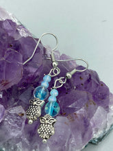 Load image into Gallery viewer, Beautiful delicate glass beaded earrings featuring silver-plated night owl charms in an enchanting pale blue hue. Measurements: 1 1/4” in length