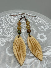 Load image into Gallery viewer, Single-stranded earring features bone carved leaf charm earrings with champagne mix melon Czech faceted round glass beads.  Glass beads have a tint of light champagne, amber, dark green and gold shimmer. Antique Copper Plated Surgical Steel Hammered Long Ear-wire French Hook Earrings.   Measurements: 3” in length