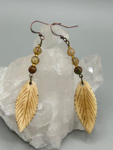 Load image into Gallery viewer, Single-stranded earring features bone carved leaf charm earrings with champagne mix melon Czech faceted round glass beads.  Glass beads have a tint of light champagne, amber, dark green and gold shimmer. Antique Copper Plated Surgical Steel Hammered Long Ear-wire French Hook Earrings.   Measurements: 3” in length