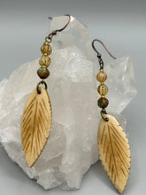 Load image into Gallery viewer, Single-stranded earring features bone carved leaf charm earrings with champagne mix melon Czech faceted round glass beads.  Glass beads have a tint of light champagne, amber, dark green and gold shimmer. Antique Copper Plated Surgical Steel Hammered Long Ear-wire French Hook Earrings.   Measurements: 3” in length