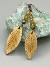 Load image into Gallery viewer, Single-stranded earring features bone carved leaf charm earrings with champagne mix melon Czech faceted round glass beads.  Glass beads have a tint of light champagne, amber, dark green and gold shimmer. Antique Copper Plated Surgical Steel Hammered Long Ear-wire French Hook Earrings.   Measurements: 3” in length