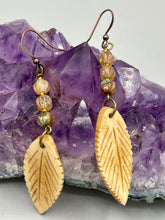 Load image into Gallery viewer, Single-stranded earring features bone carved leaf charm earrings with champagne mix melon Czech faceted round glass beads.  Glass beads have a tint of light champagne, amber, dark green and gold shimmer. Antique Copper Plated Surgical Steel Hammered Long Ear-wire French Hook Earrings.   Measurements: 3” in length