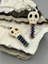 Load image into Gallery viewer, Spooky skull beads come with spine earrings. These stylish skull earrings are perfect for adding a unique flair to any outfit. Whether you're looking for a Dia De Los Muertos accessory or simply looking to draw inspiration, these goth pieces perfectly capture the vampire goth, witchy, dark, Chingona Cabrona, Latina Chicana styles. Measurements: 1 1/4” in length