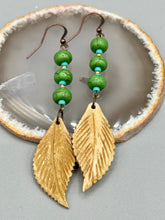 Load image into Gallery viewer, Single-stranded earring features bone carved leaf charm earrings with bright green magnesite stone and blue turquoise and gold glass beads. Antique Copper Plated Surgical Steel Hammered Long Ear-wire French Hook Earrings. Measurements: 3” in length