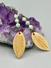 Load image into Gallery viewer, Single-stranded earring features bone carved leaf charm earrings with light mint green melon Czech faceted round glass beads.  Glass beads have a tint of light gold shimmer. Antique antique brass plated steel ear-wire French Hook Earrings.   Measurements: 3” in length