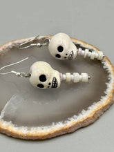 Load image into Gallery viewer, Peruvian off white ceramic skull beads come with spine earrings. These stylish skull earrings are perfect for adding a unique flair to any outfit. Whether you're looking for a Dia De Los Muertos accessory or simply looking to draw inspiration, these goth pieces perfectly capture the vampire goth, witchy, dark, Chingona Cabrona, Latina Chicana styles. Measurements: 1 1/4” in length