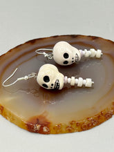 Load image into Gallery viewer, Peruvian off white ceramic skull beads come with spine earrings. These stylish skull earrings are perfect for adding a unique flair to any outfit. Whether you're looking for a Dia De Los Muertos accessory or simply looking to draw inspiration, these goth pieces perfectly capture the vampire goth, witchy, dark, Chingona Cabrona, Latina Chicana styles. Measurements: 1 1/4” in length