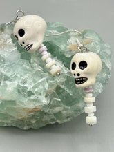 Load image into Gallery viewer, Peruvian off white ceramic skull beads come with spine earrings. These stylish skull earrings are perfect for adding a unique flair to any outfit. Whether you're looking for a Dia De Los Muertos accessory or simply looking to draw inspiration, these goth pieces perfectly capture the vampire goth, witchy, dark, Chingona Cabrona, Latina Chicana styles. Measurements: 1 1/4” in length