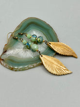Load image into Gallery viewer, Single-stranded earring features bone carved leaf charm earrings with light mint faceted round glass beads.  Glass beads have a tint of dark green and gold shimmer. Antique antique brass plated steel ear-wire French Hook Earrings.   Measurements: 3” in length